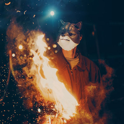 Bonfire at night with masked person